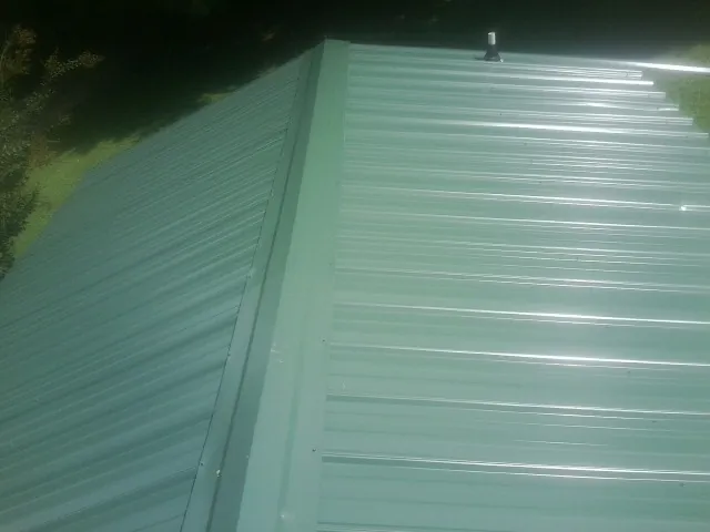 New green metal panels meeting at the ridge of a roof — Flat Roof Repair work by our crew in Narrowsburg