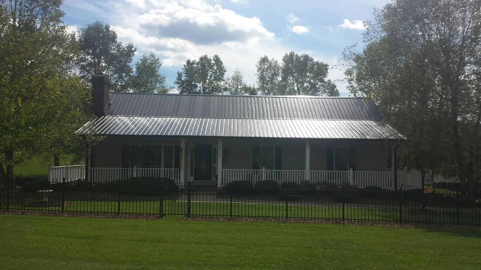 Gray metal roof on a brick ranch with a full width front porch — Gutter Guard Installation work by our crew in Narrowsburg