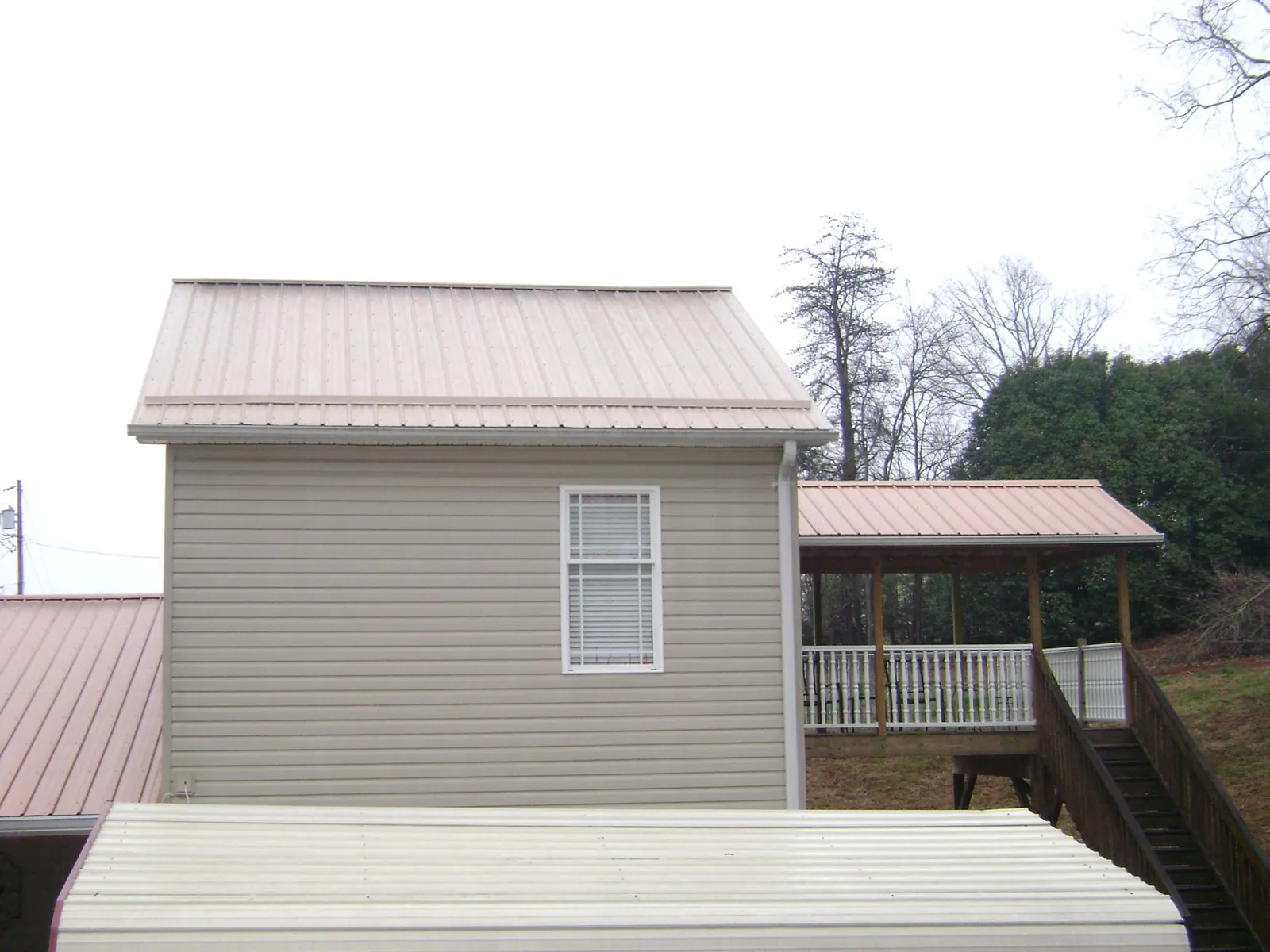 Tan metal roofs on a two story addition and attached porch, from a Roof Replacement job in Narrowsburg