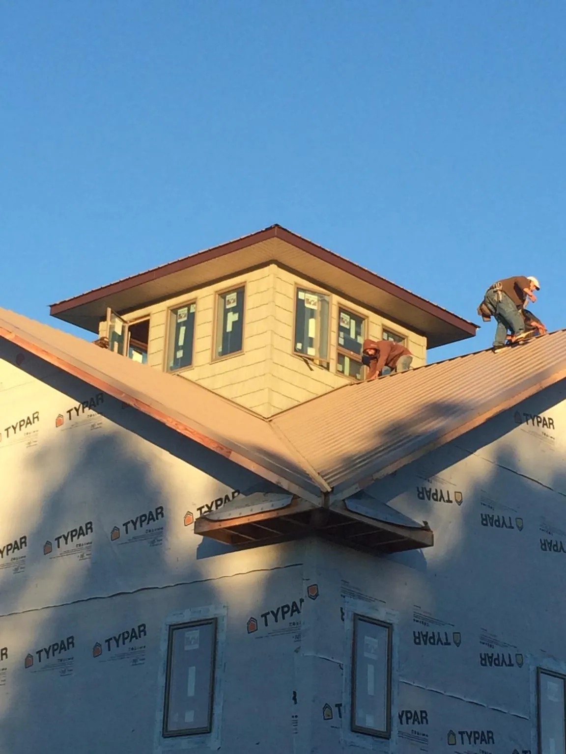 Roofers working around a rooftop cupola on a new metal roof at sunset — Roof Waterproofing in Narrowsburg by Roofing Brothers